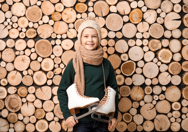 Cute little boy with ice skates against wooden