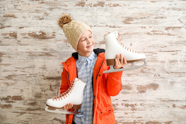 Cute little boy with ice skates against wooden