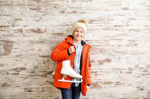 Cute little boy with ice skates against wooden