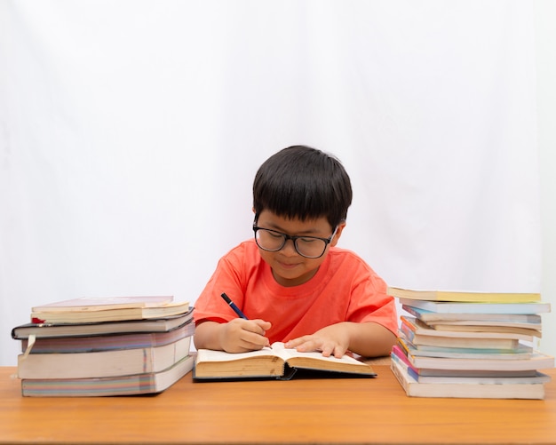 Cute a little boy writing a book on the table with on white background,