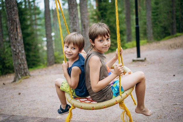 Cute little boys having fun on a swing at playground