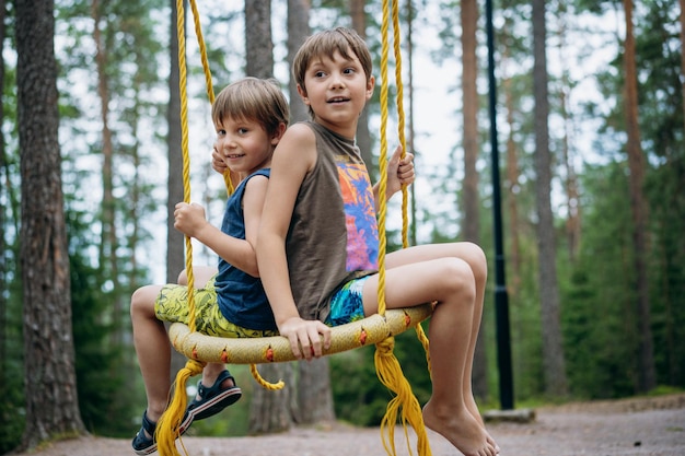 Cute little boys having fun on a swing at playground