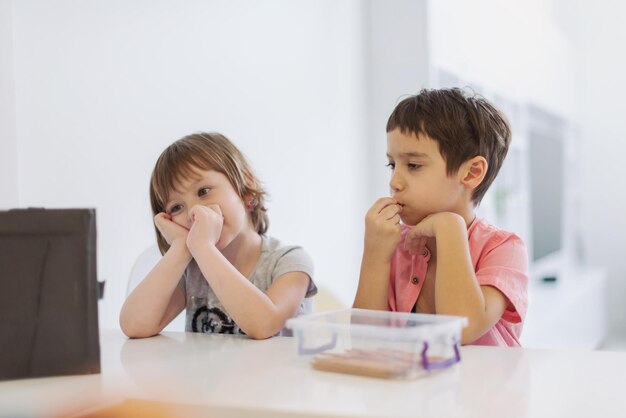 cute little brother and sister having fun at home childrends  playing games on tablet computer