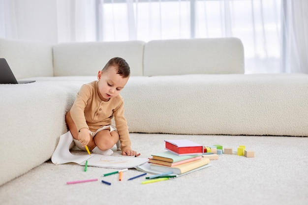 Cute little caucasian boy drawing with colorful pencils sitting on floor at home creativity concept ...