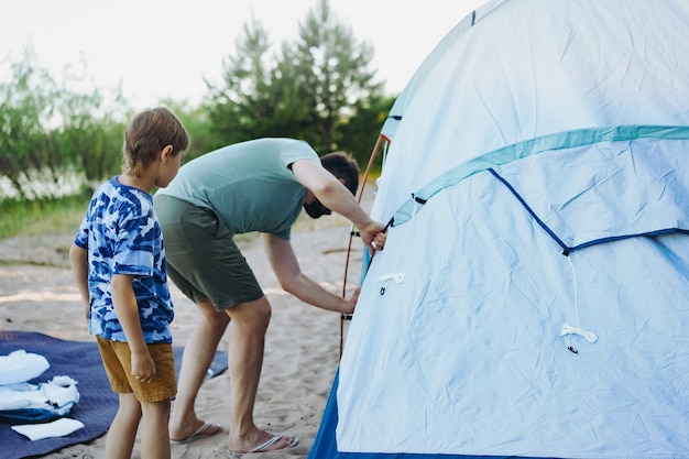 Cute little caucasian boy helping to put up a tent Family camping concept