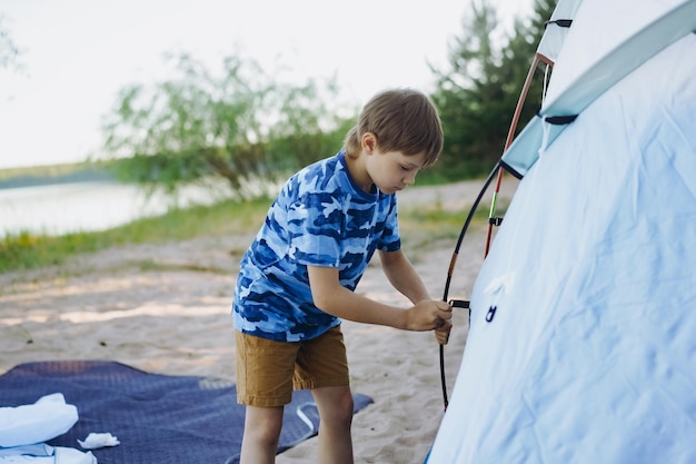 Cute little caucasian boy helping to put up a tent Family camping concept