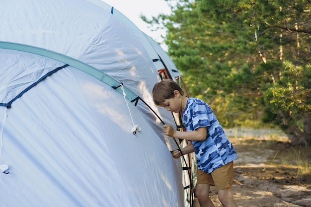 Cute little caucasian boy helping to put up a tent Family camping concept