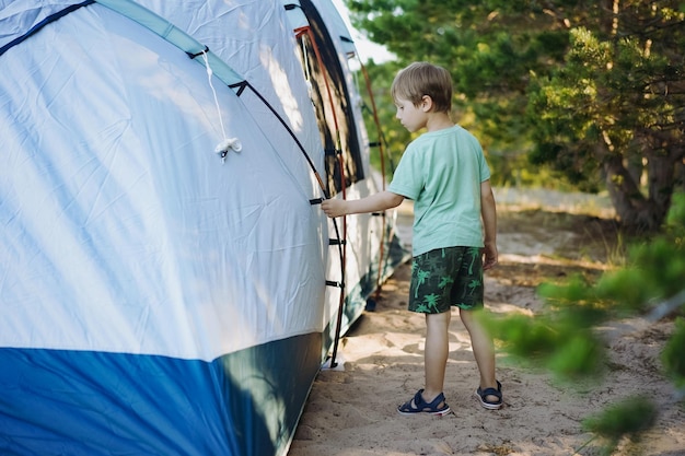 Cute little caucasian boy helping to put up a tent Family camping concept