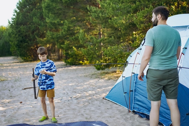 Cute little caucasian boy helping to put up a tent Family camping concept