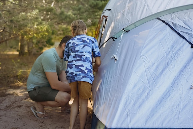 Cute little caucasian boy helping to put up a tent Family camping concept