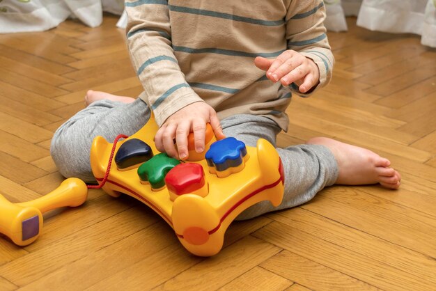 Photo cute little caucasian boy playing collects multicolored sorter constructor baby's hands puzzle sorter of plastic toy children logic development childhood daycare educationkindergarten concept