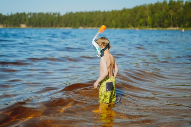 Cute little caucasian boy wearing snorkeling mask going to swim in the sea