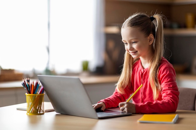 Cute little caucasian girl study with laptop and writing in notepad