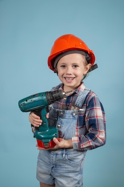 Cute little caucasian kid is wearing orange safety helmet,holding screwdriver at hands. Concept of Construction and repair.