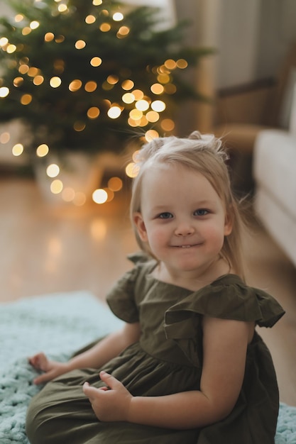 Cute little child girl and the Christmas tree indoors Merry Christmas and Happy New Year concept