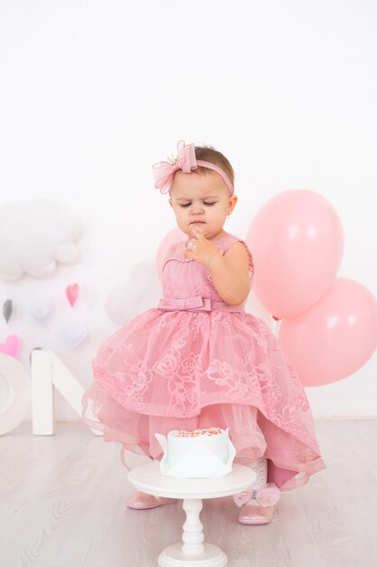 cute little child girl eating birthday cake and celebrating her first birthday