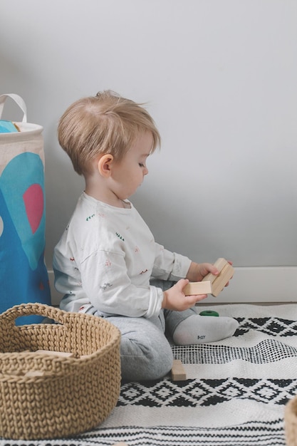 Cute little child playing with wooden toy blocks on floor at home Children's zero waste eco toys