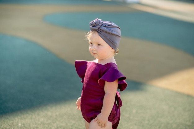 Cute little girl 1 year old on the beach at the resort in summer in a trendy outfit