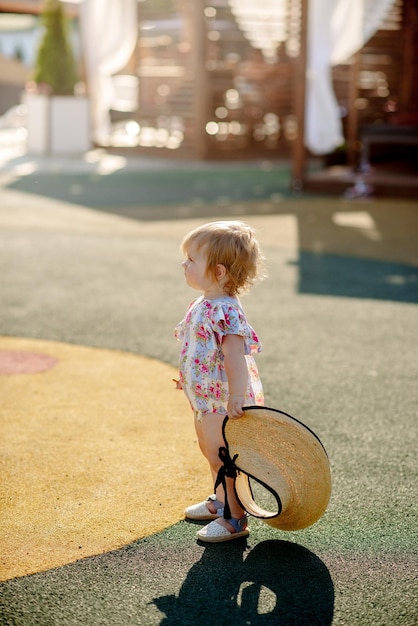 Cute little girl 1 year old on the beach at the resort in summer in a trendy outfit