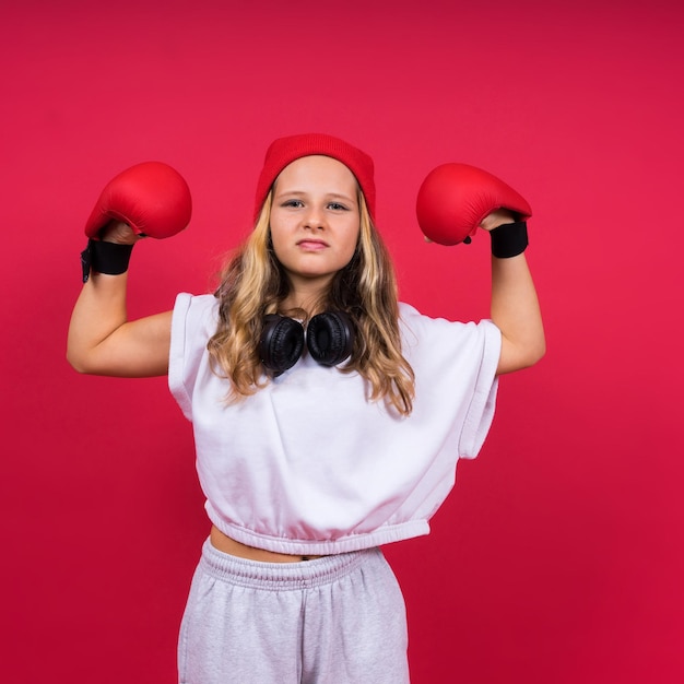 Cute little girl in boxing gloves on red background studio