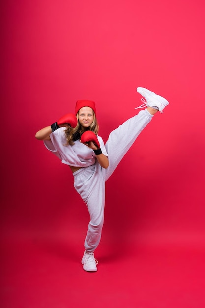 Cute little girl in boxing gloves on red background studio