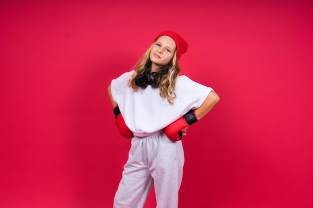 Cute little girl in boxing gloves on red background studio