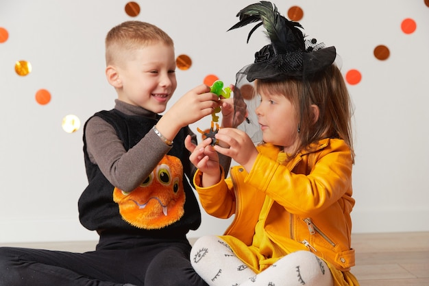 Cute little girl and boy in witch and spider costume play at home halloween party