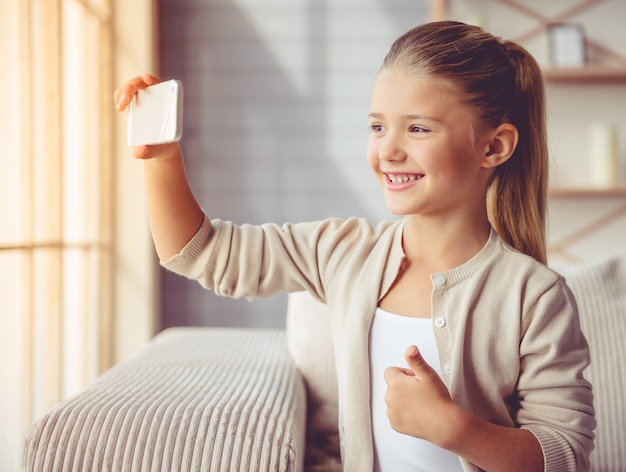 Cute little girl in casual clothes is doing selfie