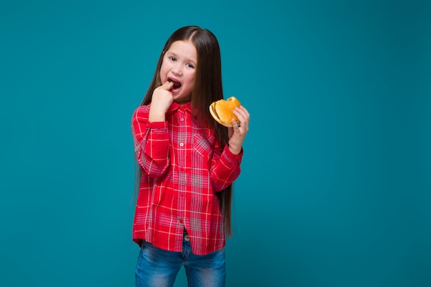 Cute little girl in checkered shirt with brunet hair hold burger