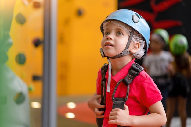 Cute little girl climber in blue protective helmet and gear for climbing