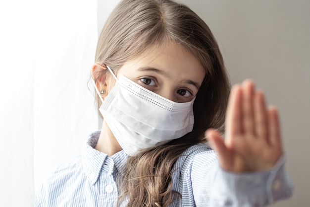 A cute little girl in a disposable protective mask from the coronavirus