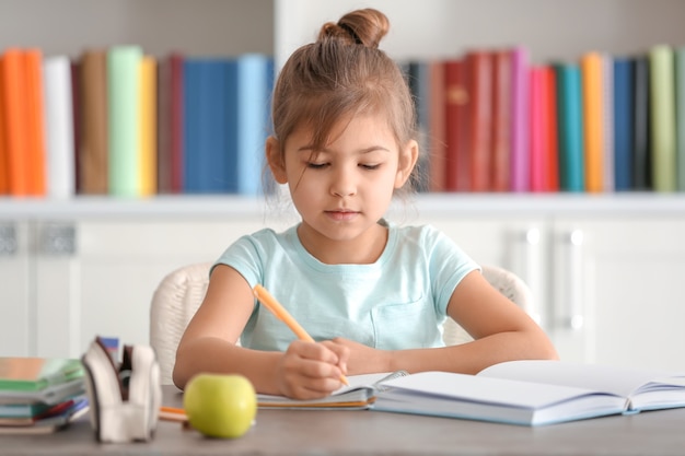 Cute little girl doing homework indoors