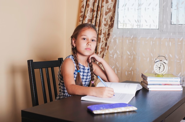 Cute little girl doing homework, reading a book, writing and painting.