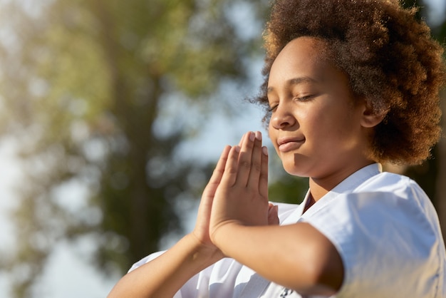 Cute little girl doing meditation exercise outdoors