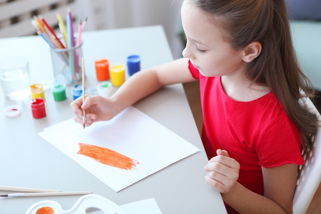 Cute little girl draws paints at home