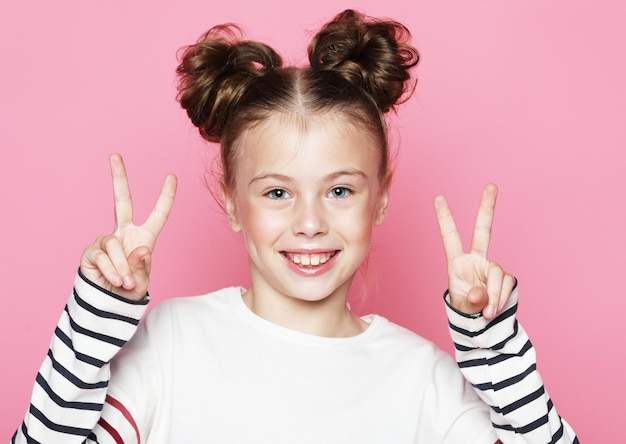 Cute little girl dressed casually posing on pink background