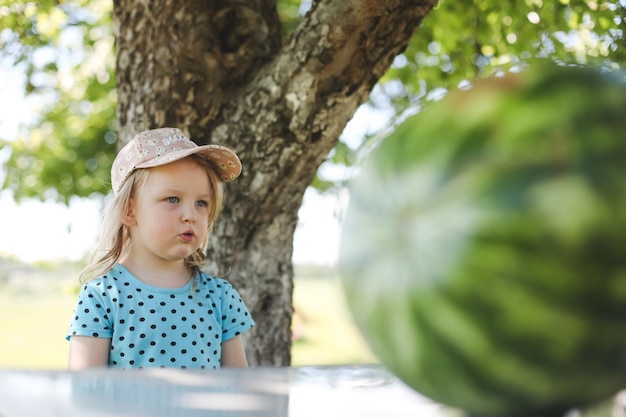 Cute little girl eating watermelon outdoors in summertime Child and watermelon in summer