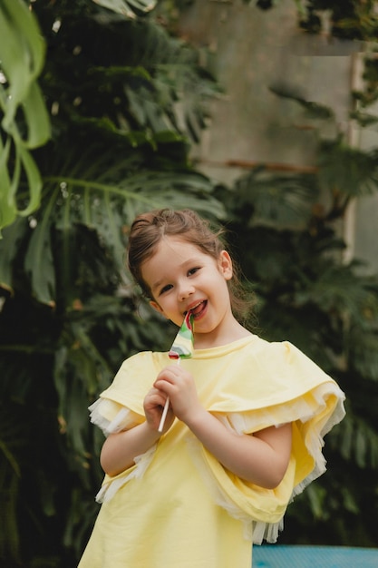 Cute little girl eating a watermelon shaped lollipop Child with lollipops in the botanical garden