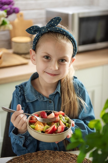 Cute little girl eats fruit salad