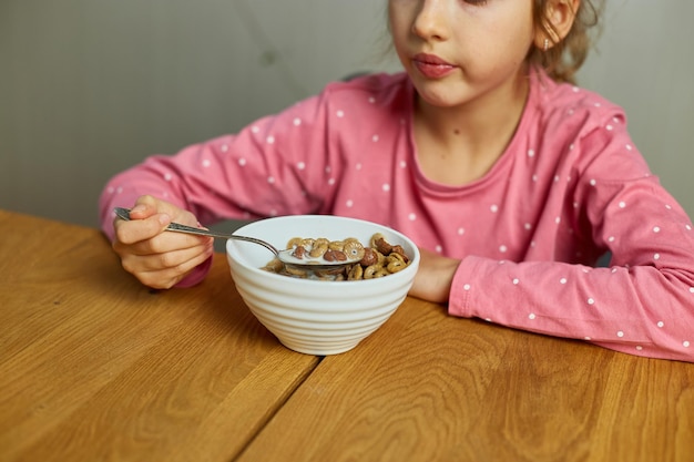 Cute little girl enjoy eating cereal with milk for morning breakfast with appetite