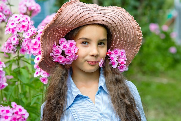 Cute little girl in hat with pink flowers phlox