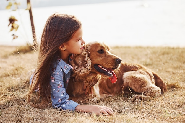 Cute little girl have a walk with her dog outdoors at sunny day