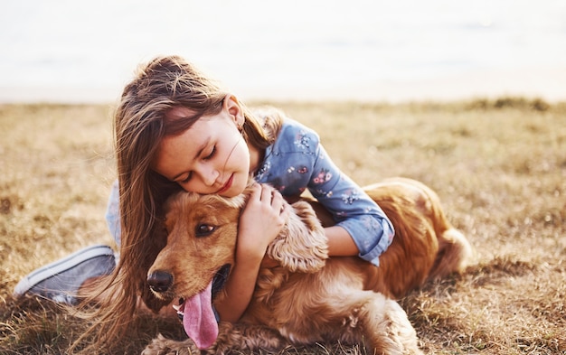 Cute little girl have a walk with her dog outdoors at sunny day