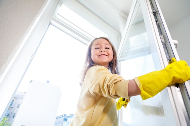 Cute little girl helping parents with cleaning the window at springtime