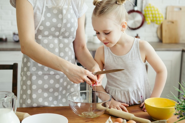 Cute little girl helps mom bake cookies in the kitchen. Happy family. Toning.