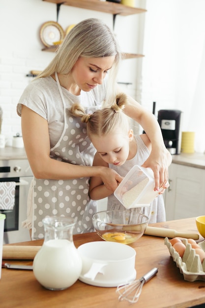 Cute little girl helps mom bake cookies in the kitchen. Happy family. Toning.