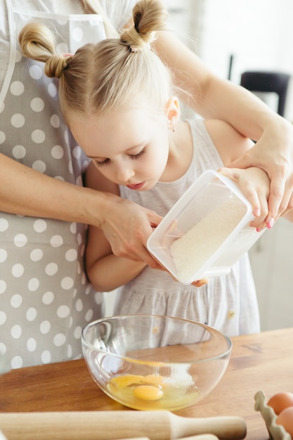 Cute little girl helps mom bake cookies in the kitchen. Happy family. Toning.