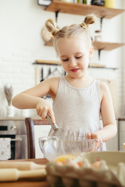 Cute little girl helps mom bake cookies in the kitchen. Happy family. Toning.