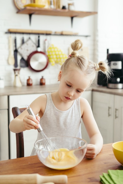 Cute little girl helps mom bake cookies in the kitchen. Happy family. Toning.