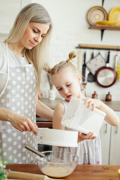 Cute little girl helps mom bake cookies in the kitchen. Happy family. Toning.